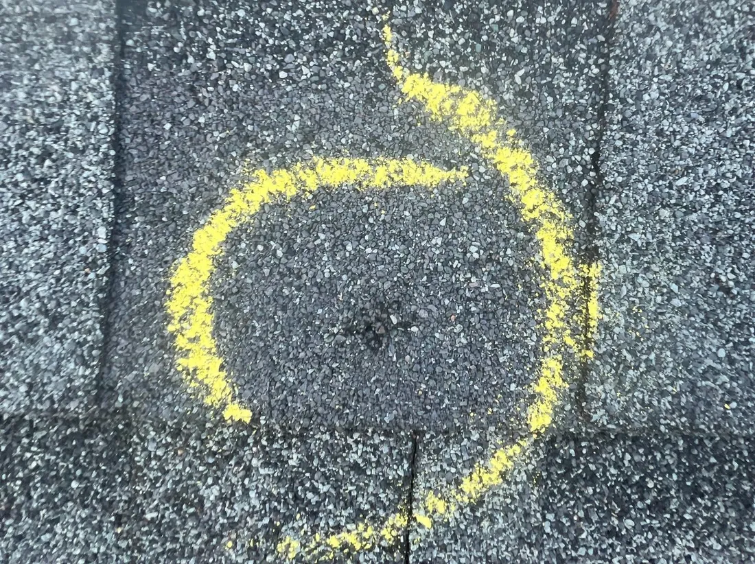 A single impact on a shingle, circled in yellow chalk.